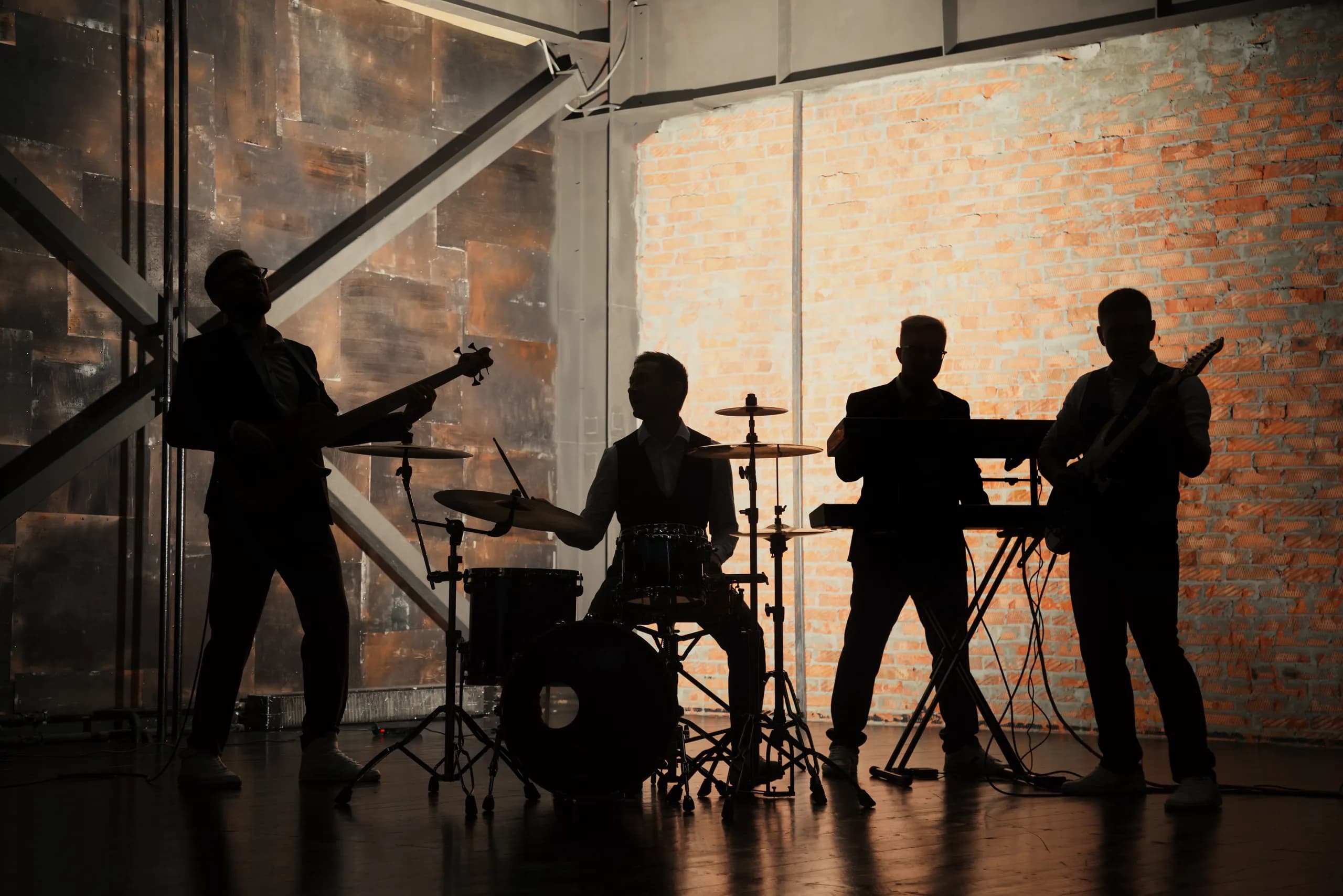 A four-piece band playing in silhouette