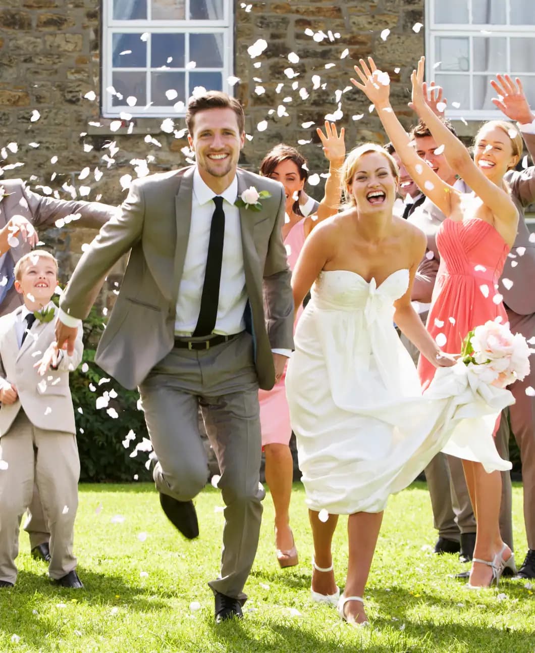 A newly married couple running through confetti with their wedding party